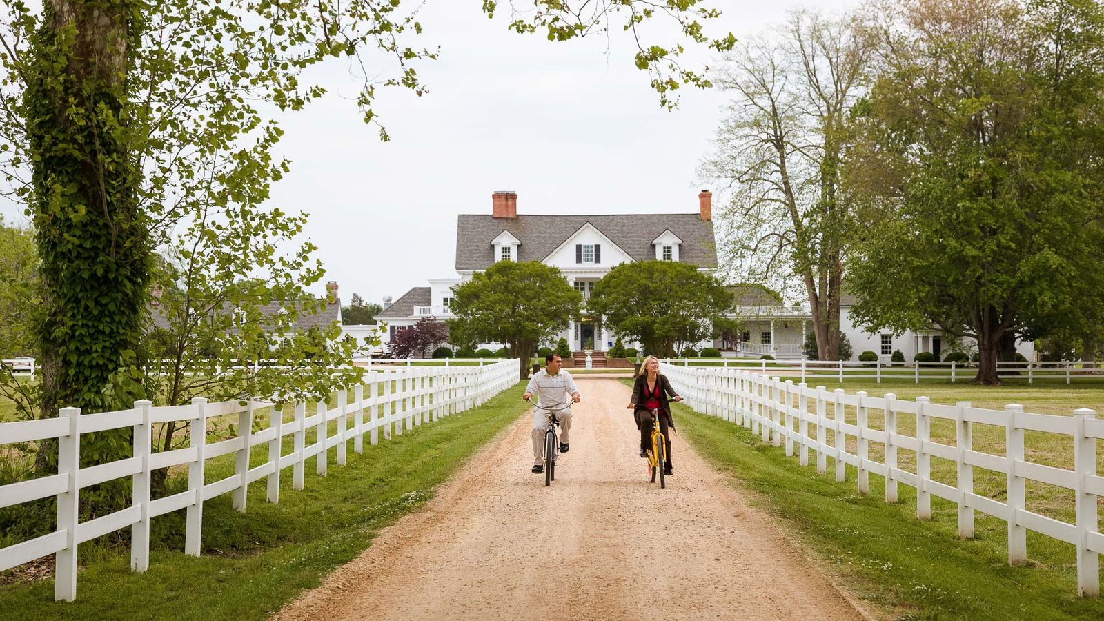 Guests cycling down the fenced drive toward the inn